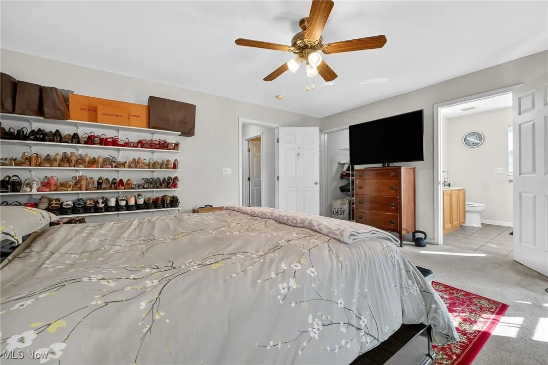 Primary bedroom with a ceiling fan and ensuite bathroom