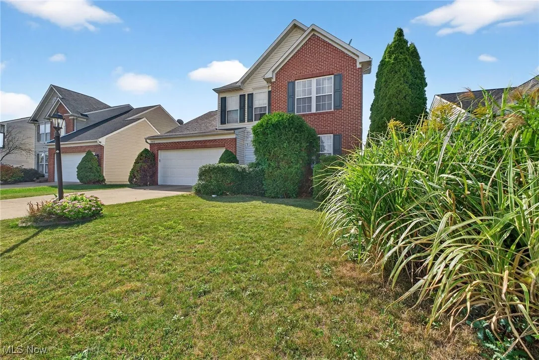Traditional-style home featuring brick siding, concrete driveway, a front yard, and a garage