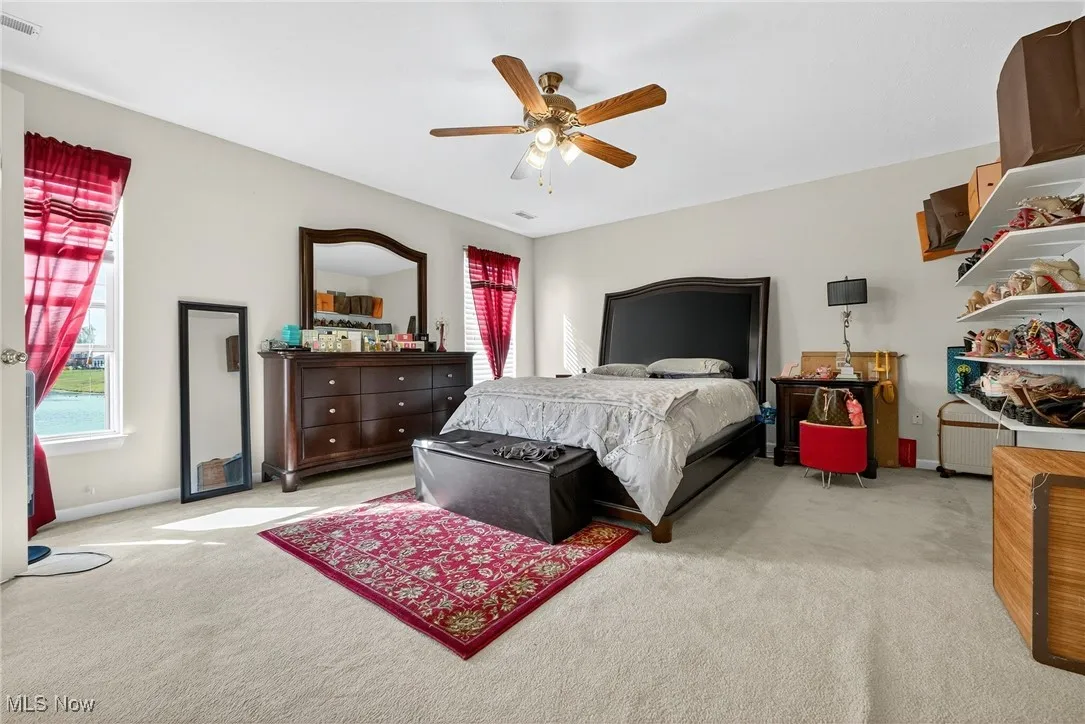 Promary bedroom with ceiling fan, light colored carpet, and radiator heating unit