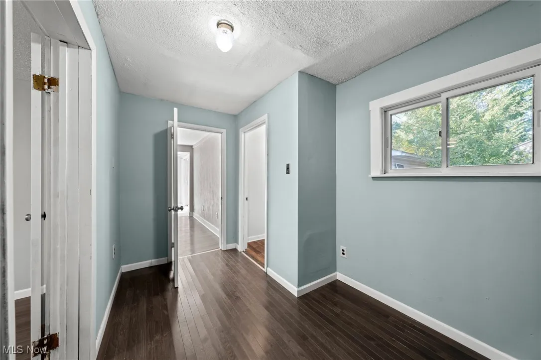 Unfurnished bedroom with dark wood-type flooring, a closet, and a textured ceiling