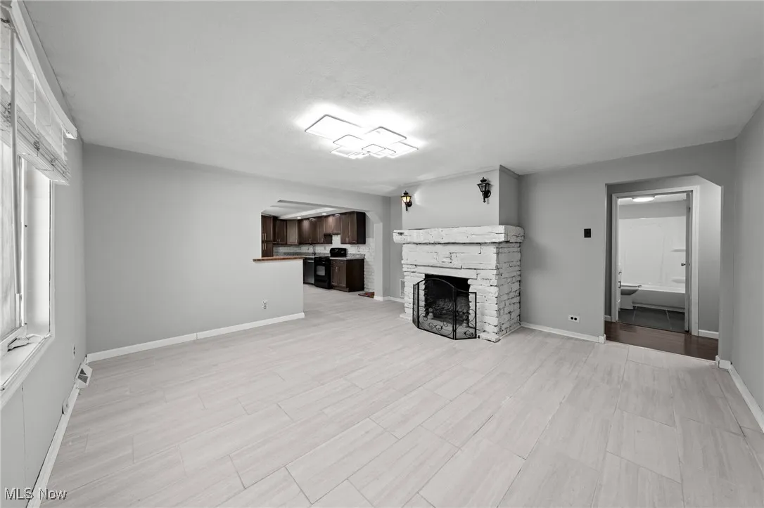 Unfurnished living room with wood tiled floors and a stone fireplace