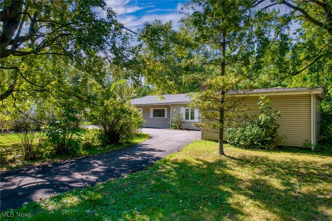 View of front of property featuring asphalt driveway and a front yard