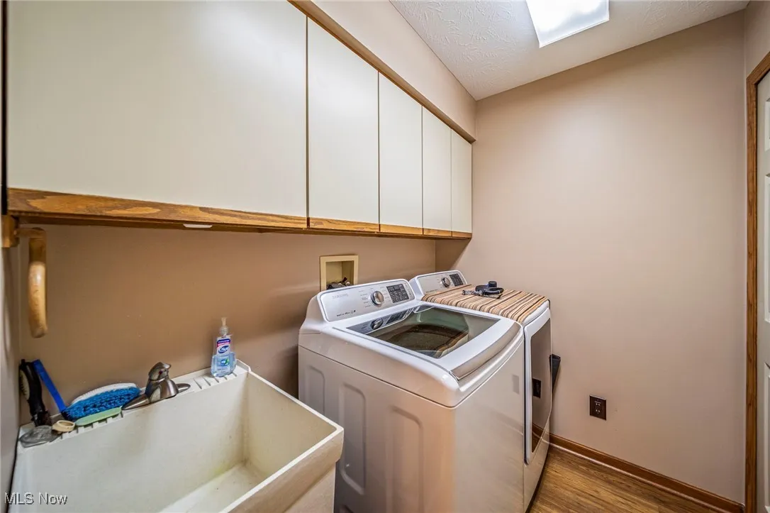 Laundry area with washing machine and dryer, cabinet space, and utility sink