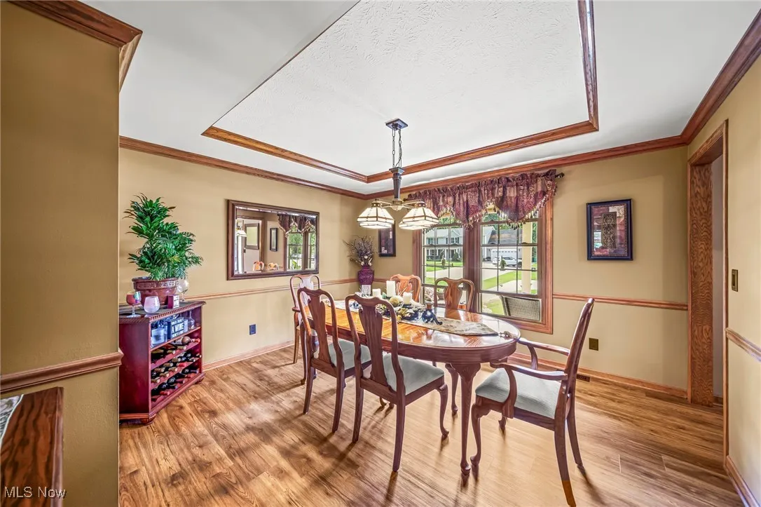 Dining room with a tray ceiling, light wood-style floors and ornamental molding