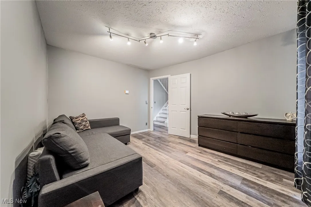 Living area featuring light wood finished floors, a textured ceiling, and stairs