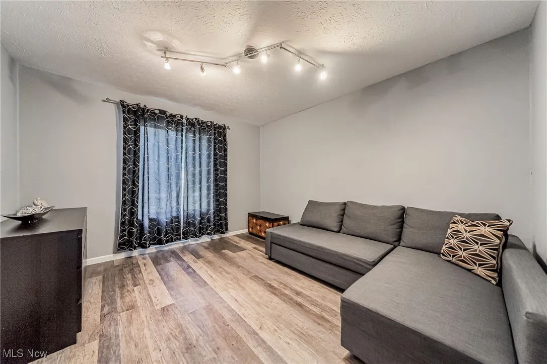 Living room featuring light wood finished floors, a textured ceiling, and rail lighting
