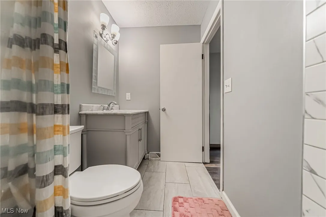 Bathroom with vanity, a textured ceiling, and a shower with shower curtain