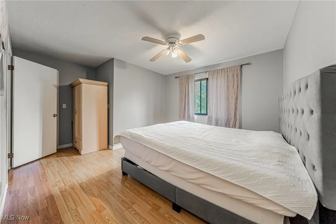 Bedroom with light wood-style flooring, ceiling fan, and a textured​​‌​​​​‌​​‌‌​‌‌​​​‌‌​‌​‌​‌​​​‌​​ ceiling