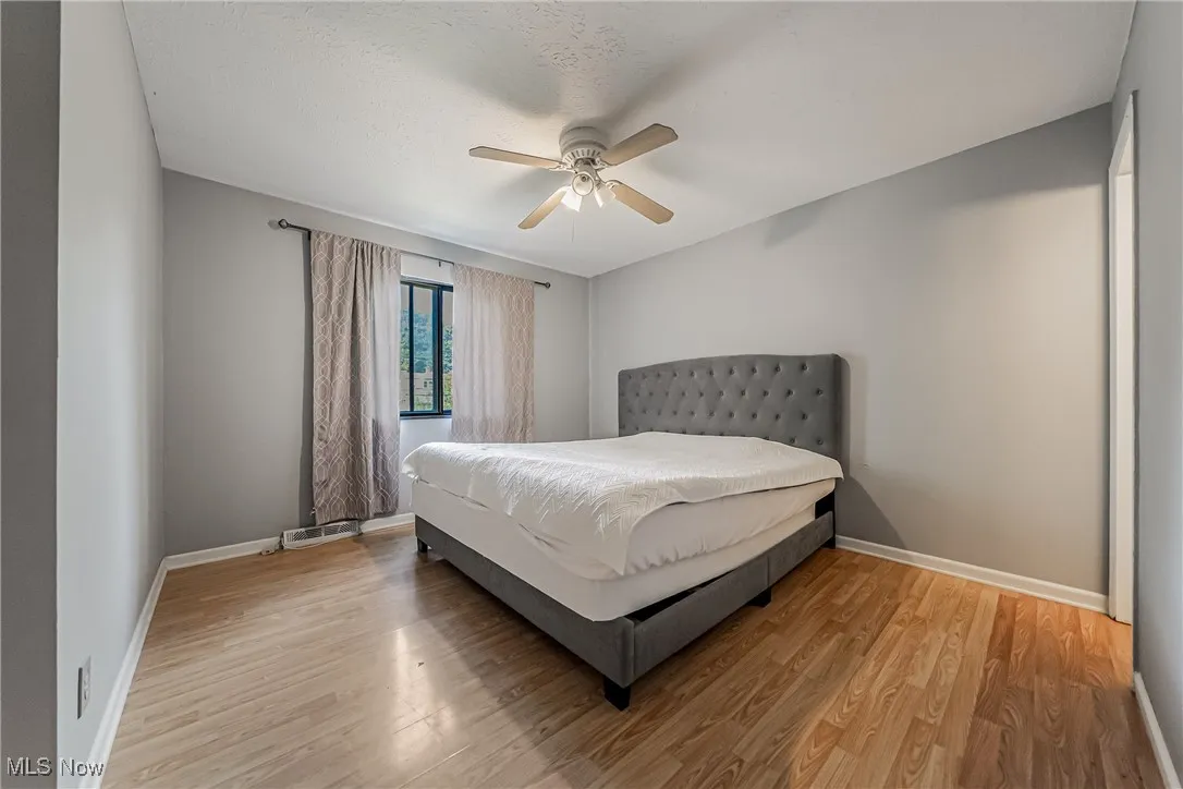 Bedroom featuring light wood finished floors, a ceiling fan, and a textured ceiling