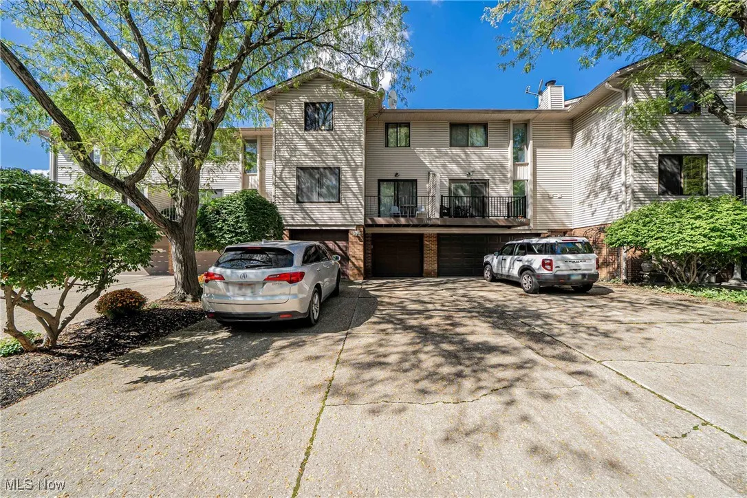 View of front of house featuring concrete driveway, a garage, a chimney, and a balcony