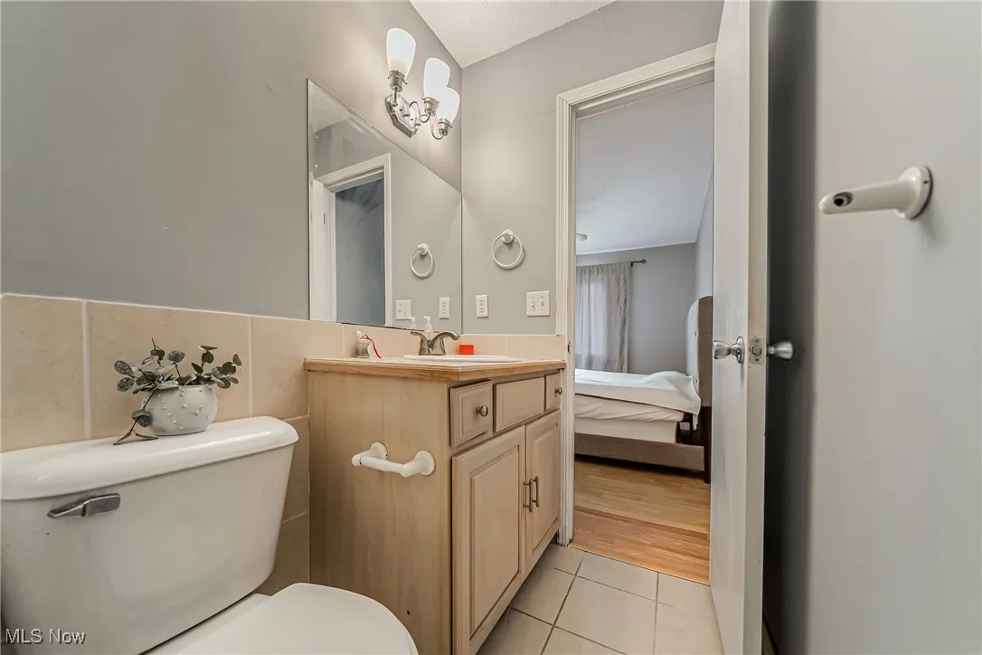 Ensuite bathroom with light tile patterned floors, vanity, and tile walls