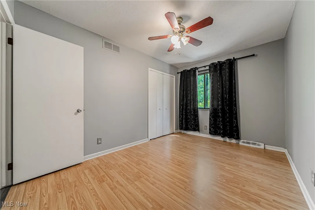 Empty room with light wood-style flooring, a ceiling fan, and a textured ceiling