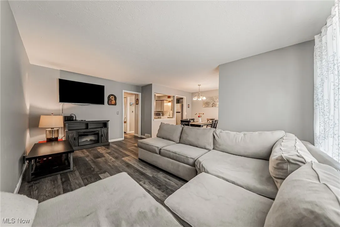 Living area featuring dark wood-style flooring and a chandelier