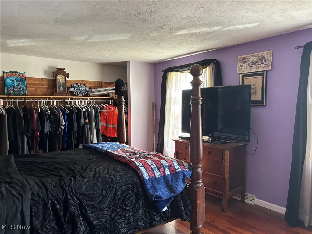 Bedroom featuring a textured ceiling, dark wood-type flooring, and a closet
