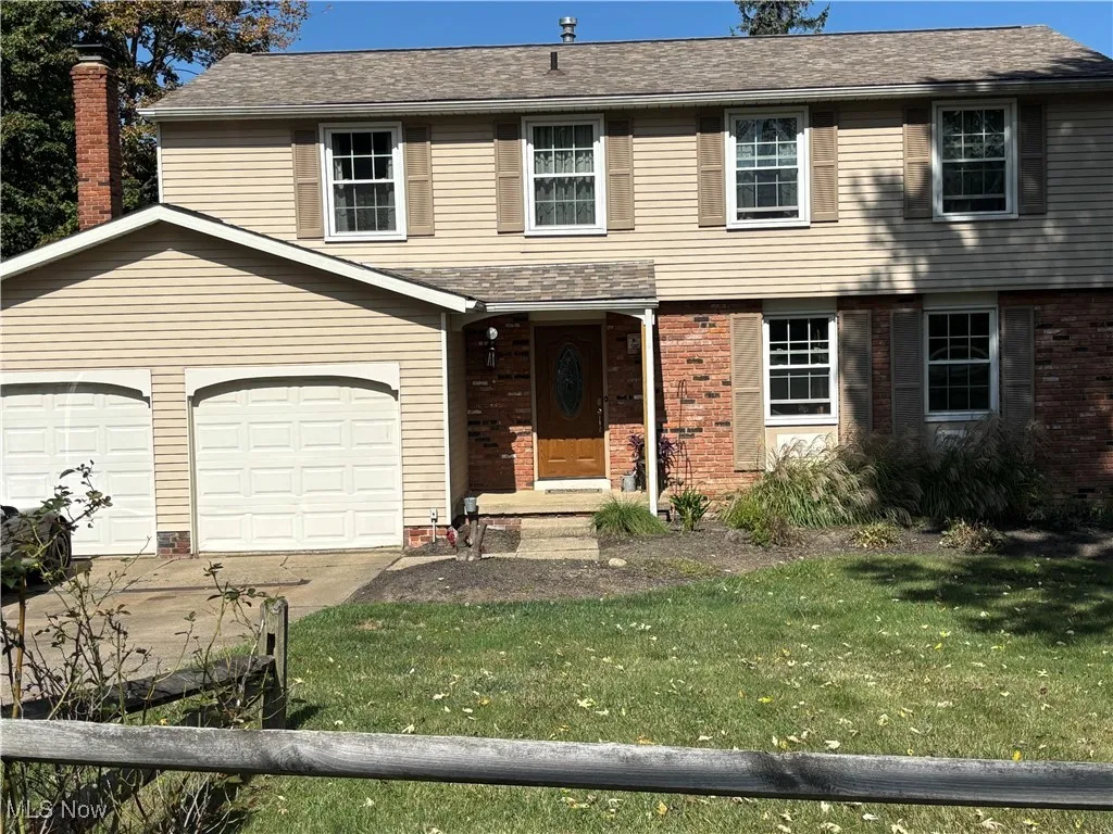 View of front of home with a front yard, driveway, brick siding, and roof with shingles