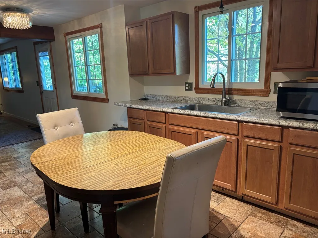 Kitchen featuring stainless steel microwave, stone tile floors, and brown cabinetry
