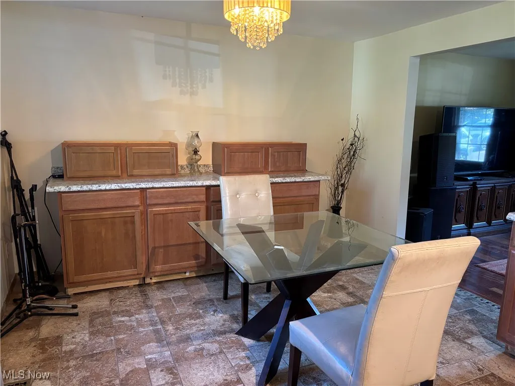 Dining room with dark stone finish flooring and a chandelier
