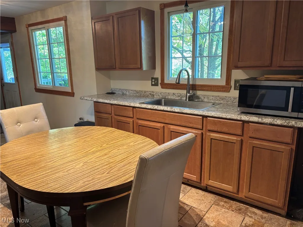 Kitchen featuring stainless steel microwave, plenty of natural light, and brown cabinetry