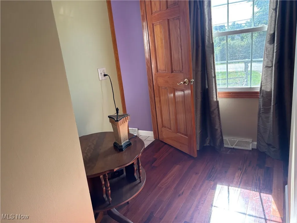 Corridor with dark wood-style flooring and baseboards