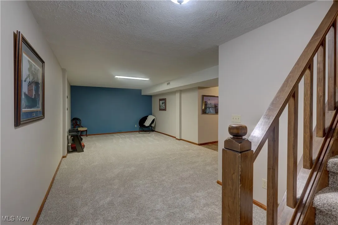 Finished basement featuring a textured ceiling and carpet flooring