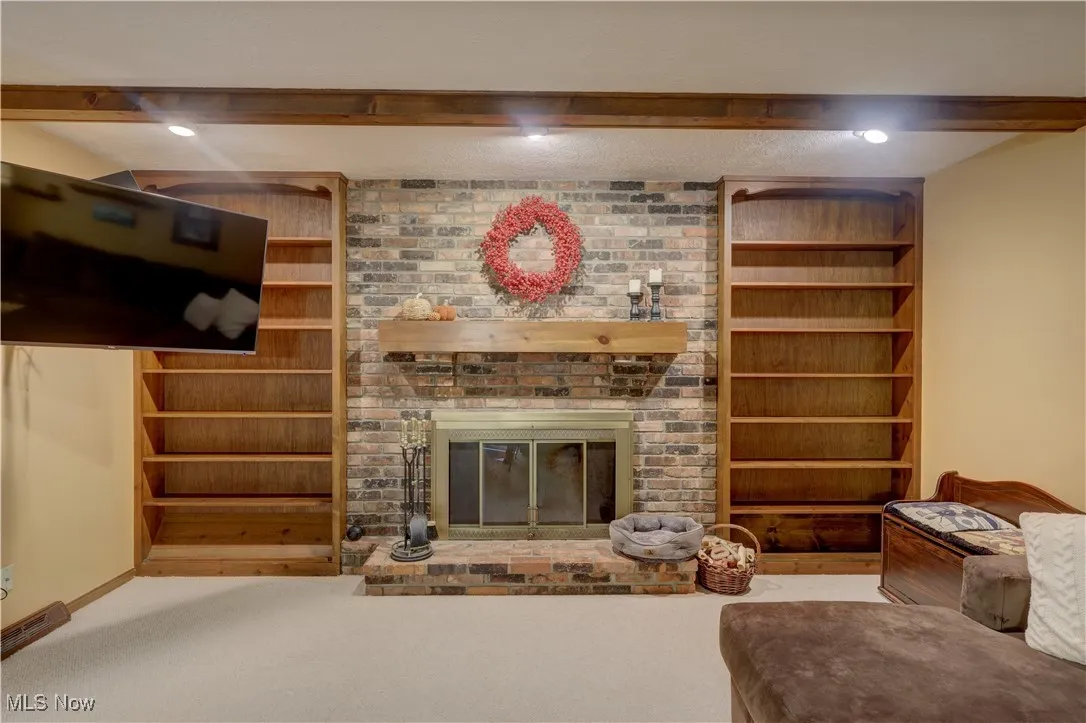 Living room with a fireplace, carpet flooring, beam ceiling, and recessed lighting