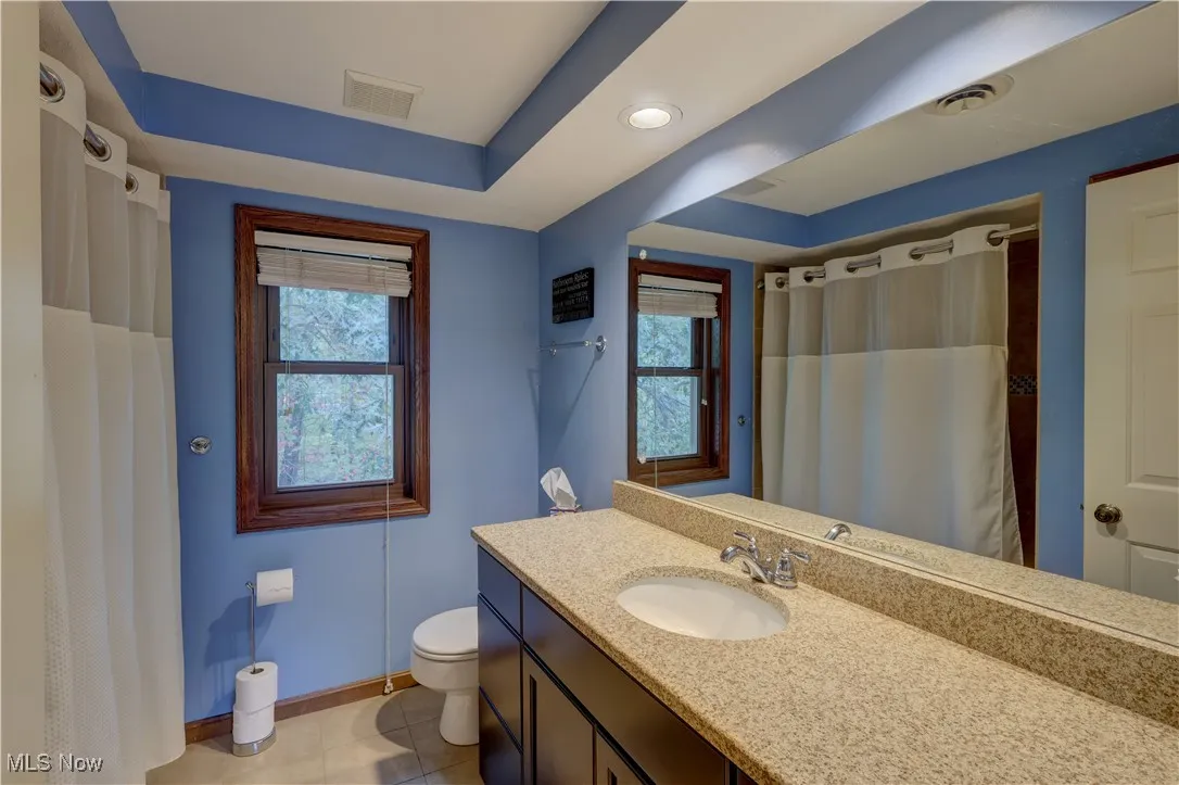 Bathroom featuring vanity, healthy amount of natural light, light tile patterned floors, and a raised ceiling