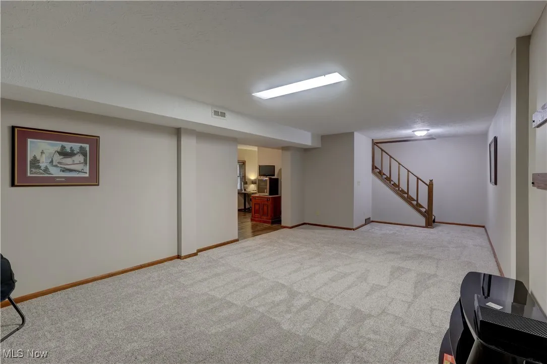 Finished basement with light carpet and stairs