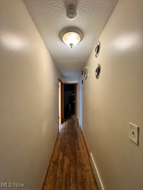 Hall featuring wood finished floors and a textured ceiling