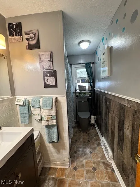 Bathroom with wainscoting, a textured ceiling, and vanity