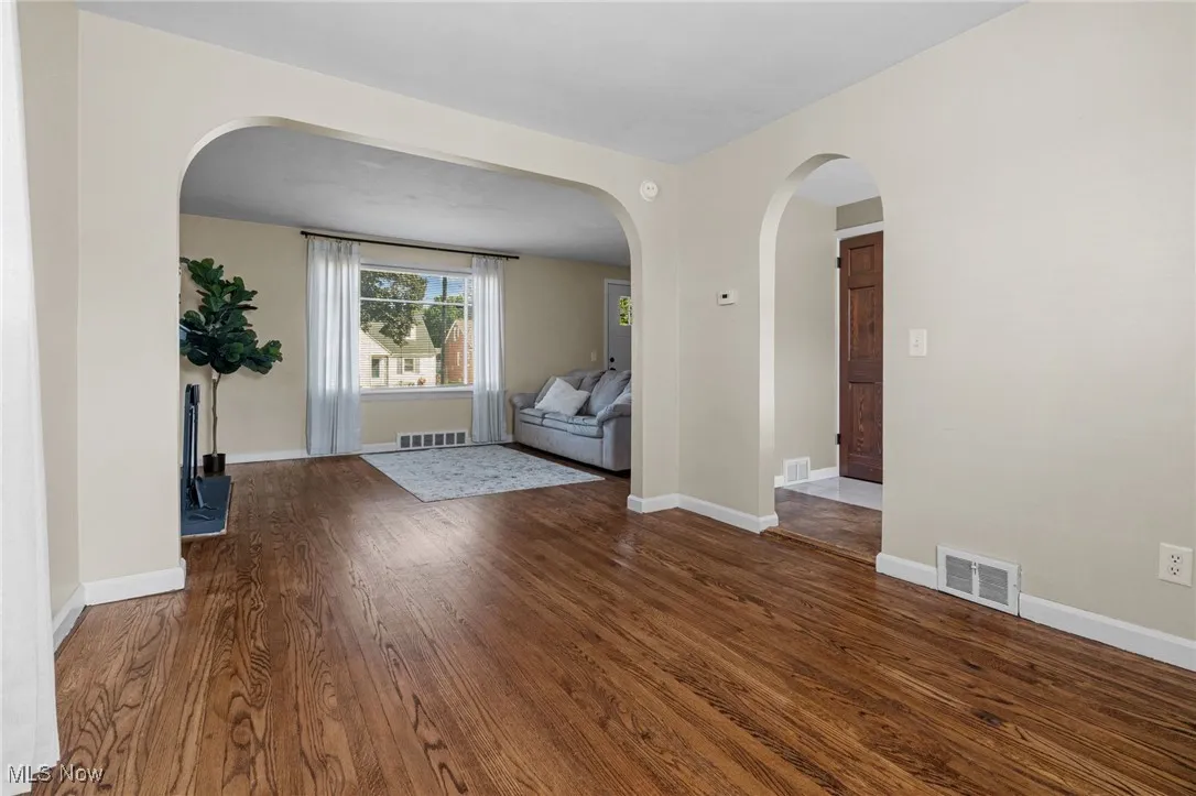 Dining room with wood floors looking into the living room.