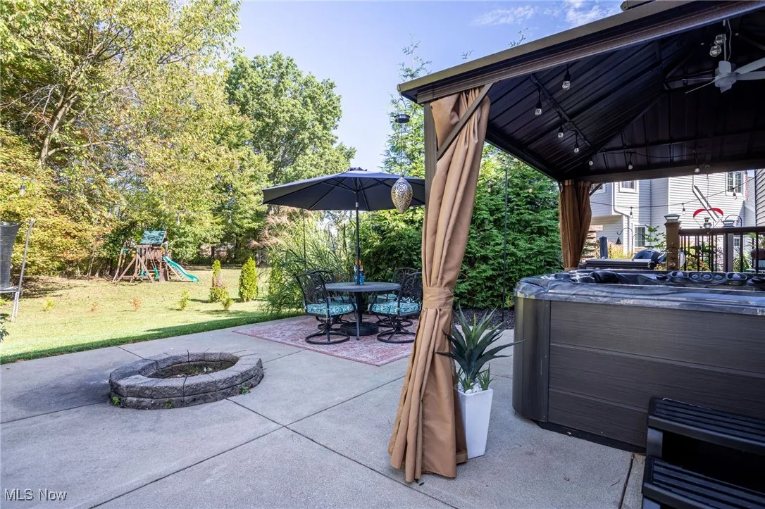 View of patio / terrace with an outdoor fire pit, a gazebo, a playground, a hot tub, and outdoor dining space