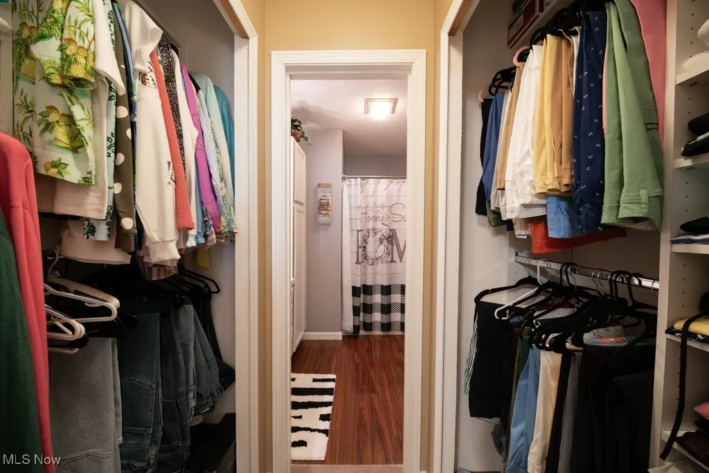 Spacious walk-in closet featuring dark wood finished floors