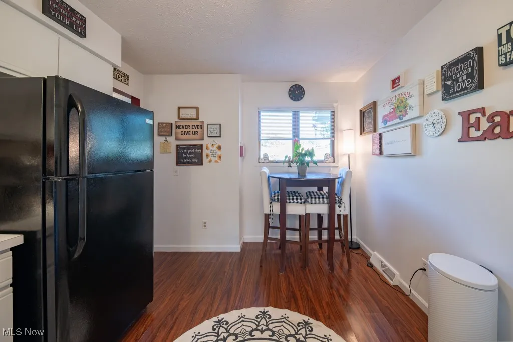 Kitchen featuring freestanding refrigerator, dark wood finished floors, white cabinets, and light countertops