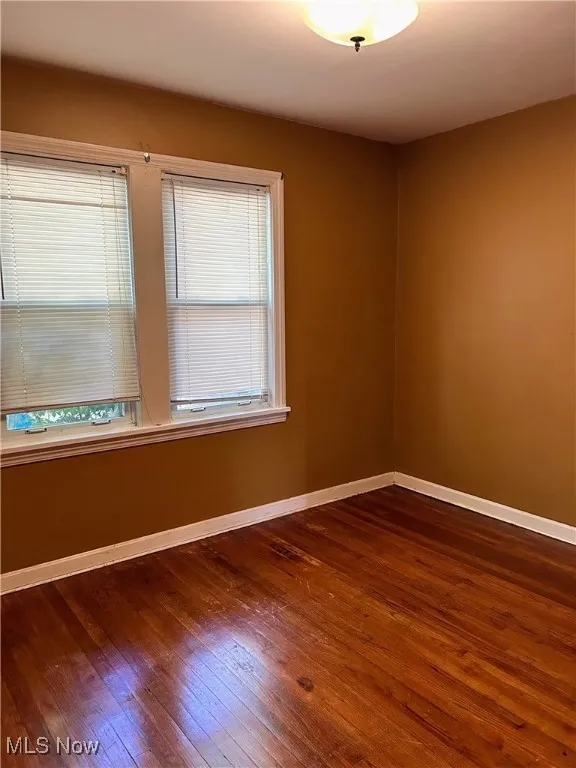 Unfurnished room featuring baseboards and dark wood finished floors