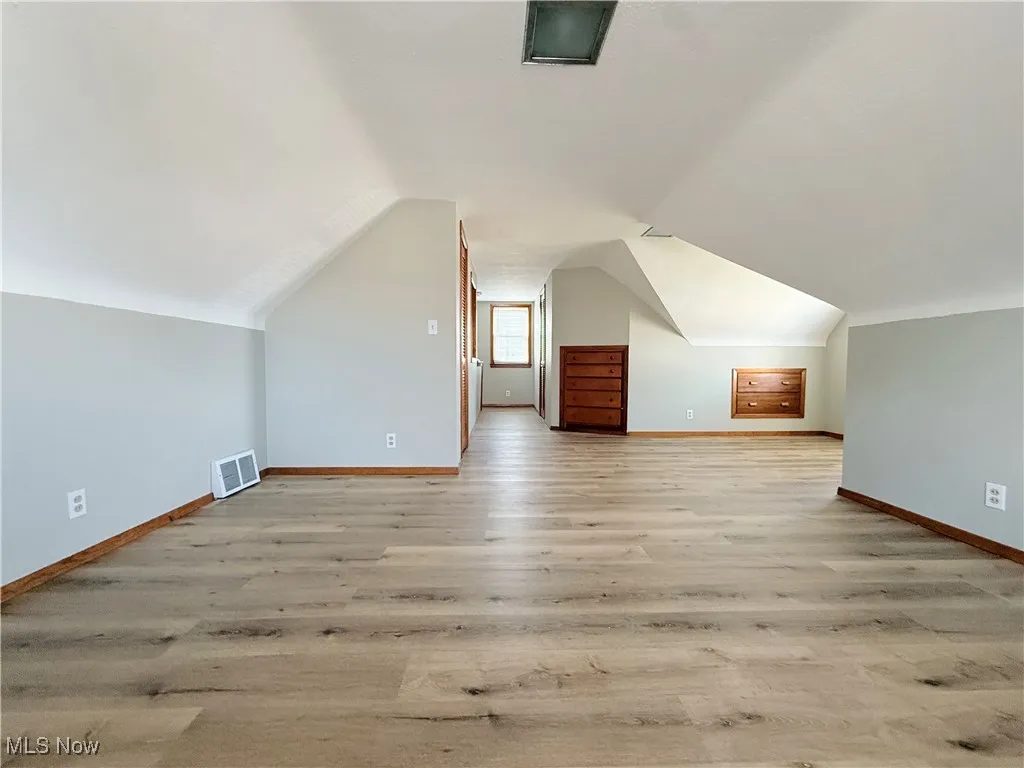 Bonus room with light wood-type flooring and lofted ceiling