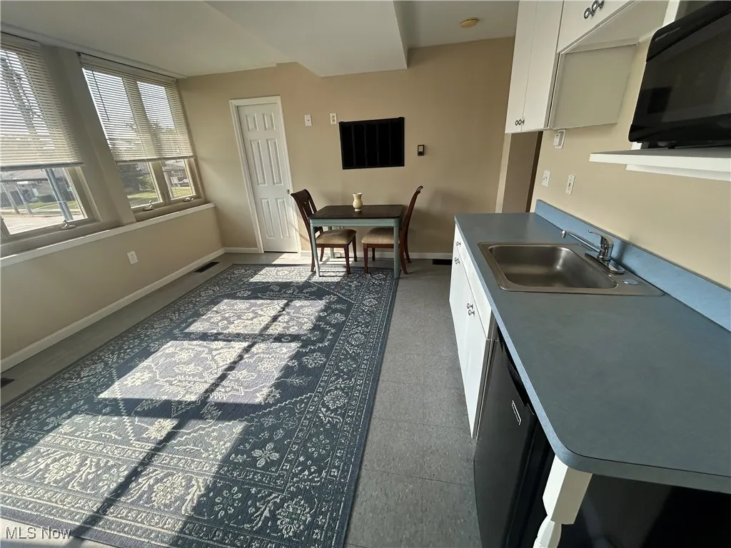 Kitchen with black appliances, white cabinetry.