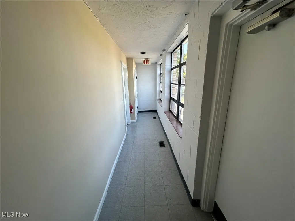 Corridor with vinyl tiled flooring a nd a textured ceiling with doorway leading to Apartments.
