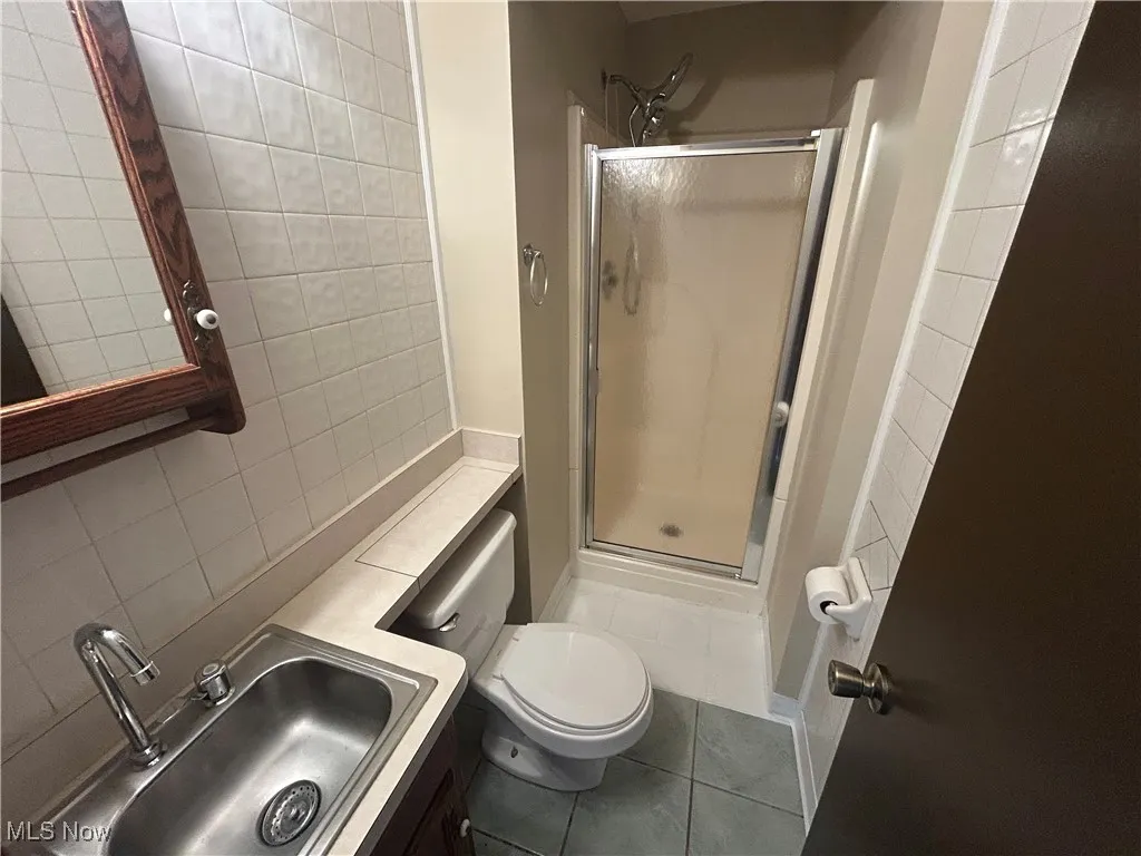 Full bath featuring a stall shower, vanity, tile patterned flooring, , tiled walls acd ceiling