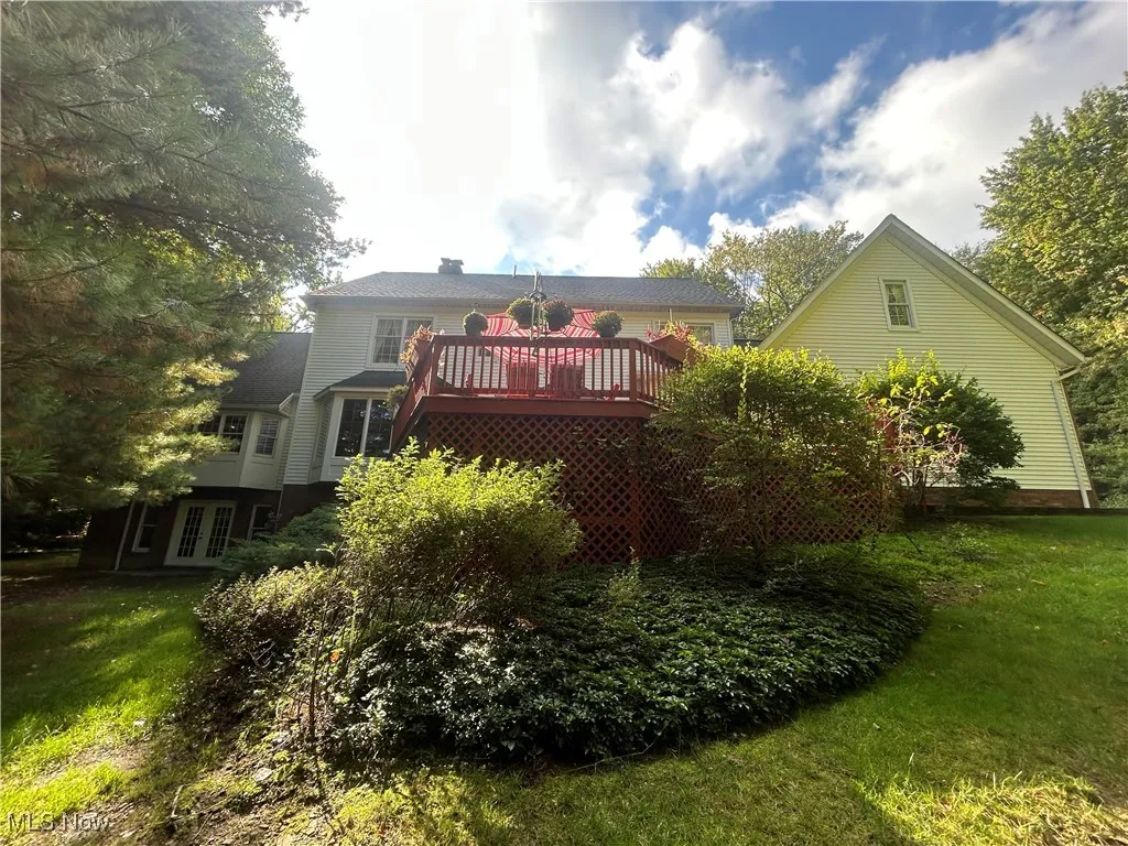 Back of property with a lawn, a deck, and french doors