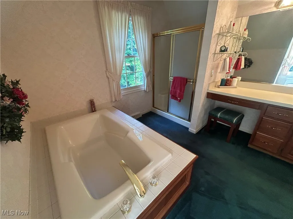 Full bathroom with a bath, vanity, and a stall shower