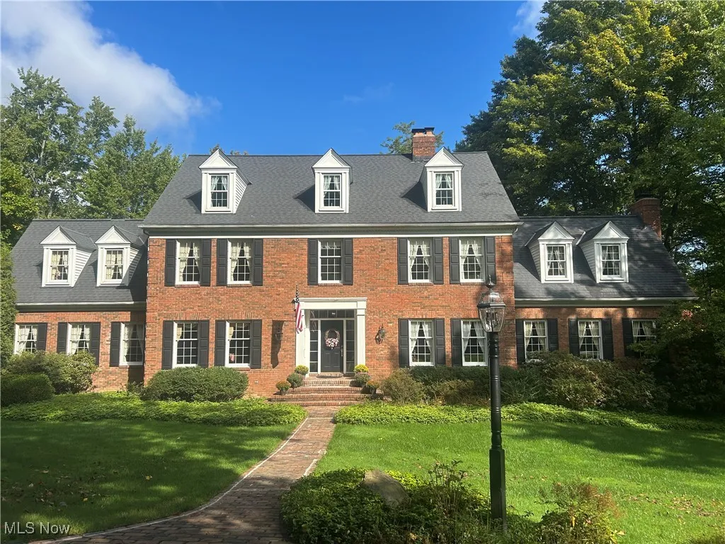 View of front of property with a front lawn, a chimney, and brick siding