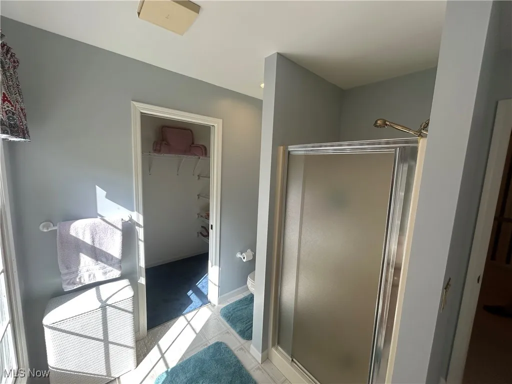 Bathroom with a shower stall, a walk in closet, and light tile patterned floors