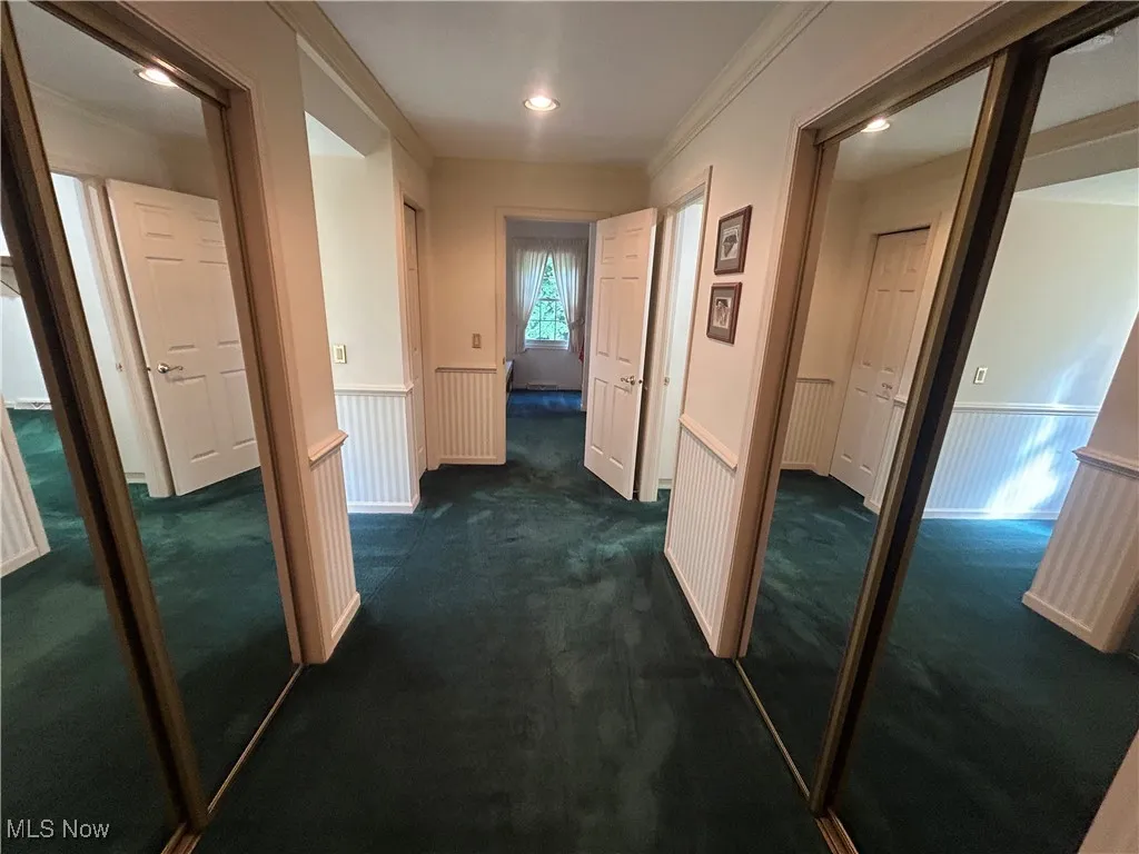 Hall with wainscoting, dark carpet, recessed lighting, and ornamental molding