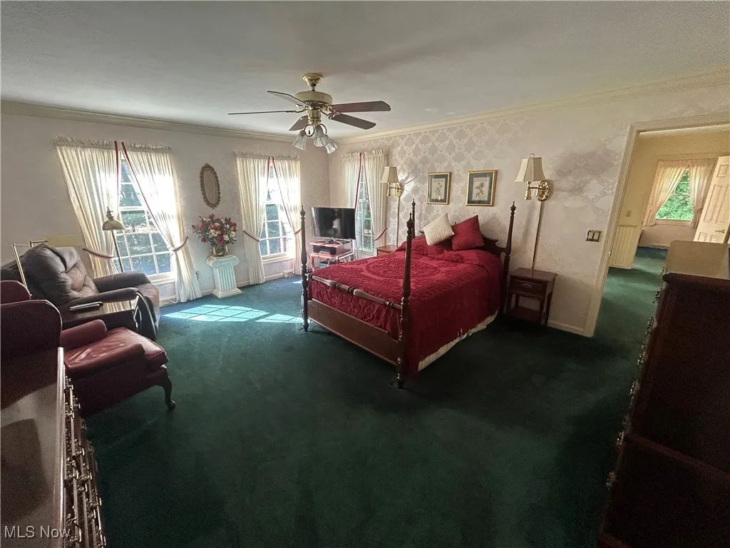Bedroom featuring ornamental molding, wallpapered walls, carpet, and ceiling fan