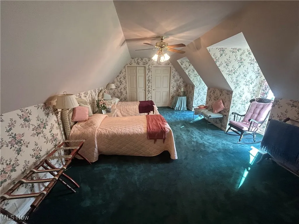Bedroom with wallpapered walls, carpet floors, lofted ceiling, and ceiling fan