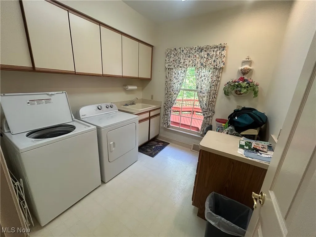 Laundry area with light flooring, washer and dryer, and cabinet space