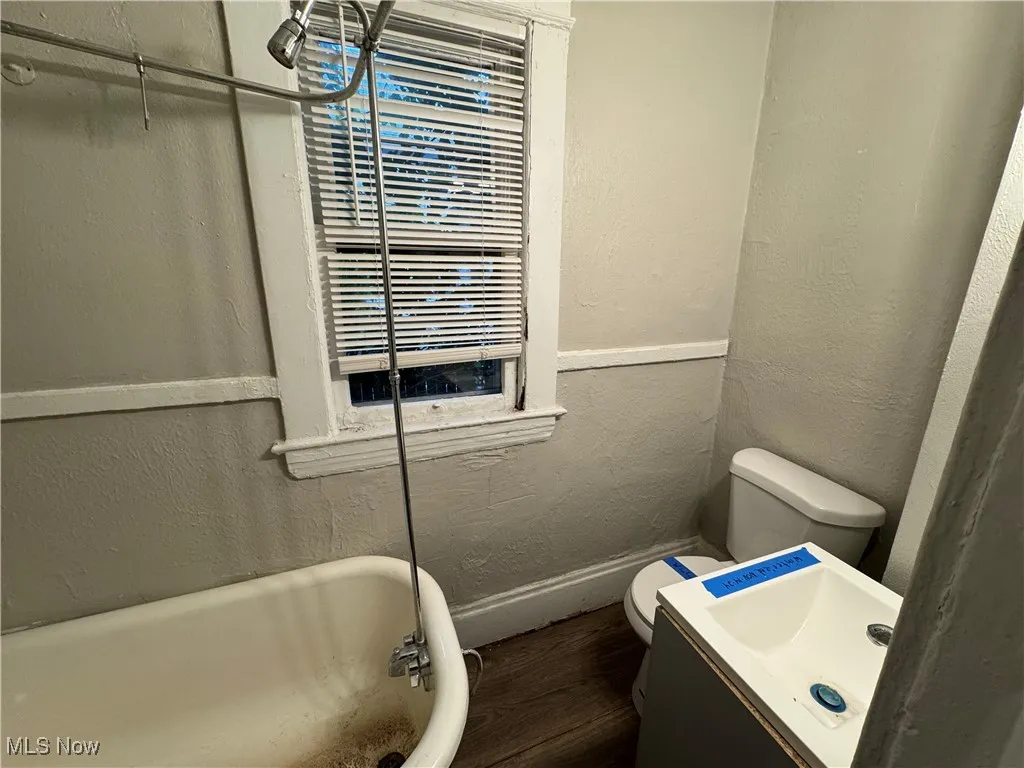 Bathroom featuring a textured wall, a freestanding tub, vanity, and dark wood-style floors