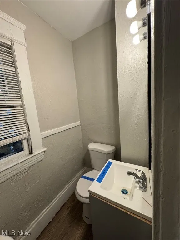 Bathroom with a textured wall, vanity, and dark wood-style floors