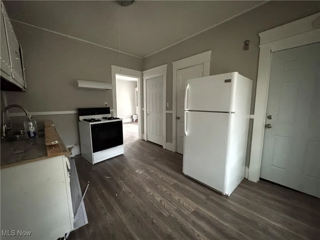Kitchen featuring white appliances, dark wood finished floors, white cabinetry, exhaust hood, and light stone counters