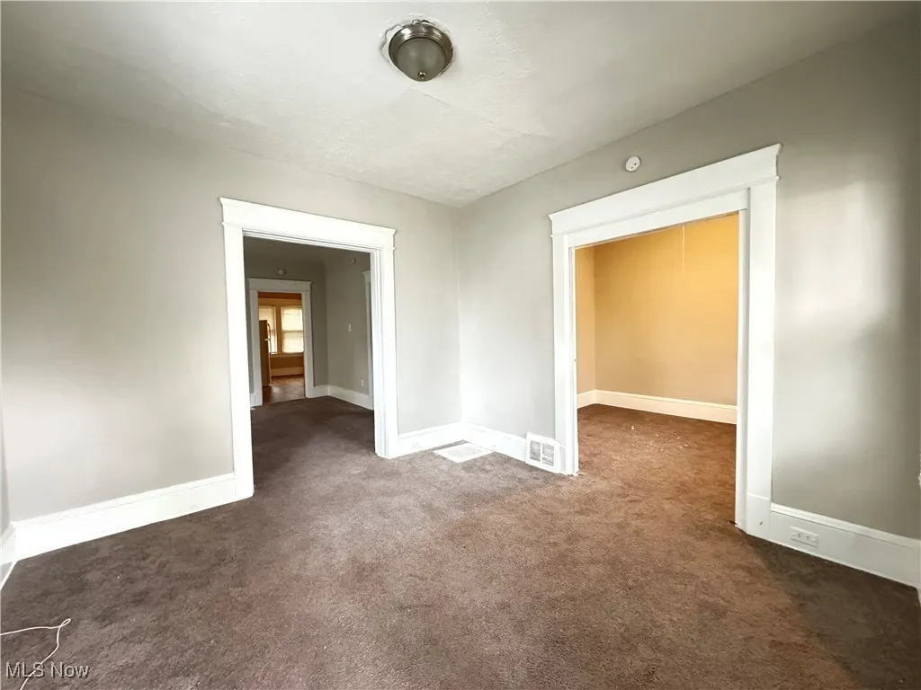 Spare room featuring dark carpet and baseboards